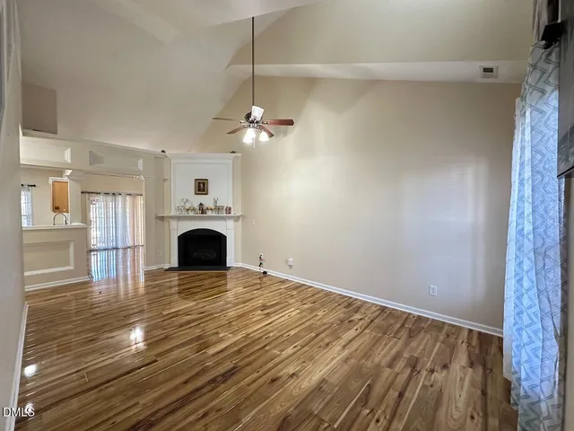 a view of empty room with fireplace and wooden floor