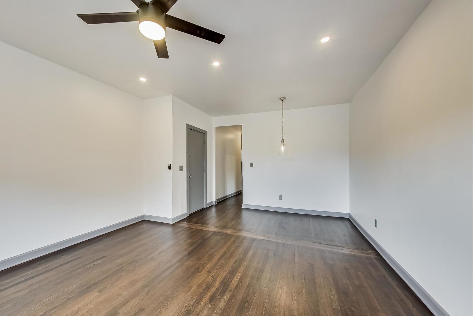 3263 North Broadway, Unit 3 Chicago, IL 60657 - Photo 16 of 37 an empty room with wooden floor a ceiling fan and kitchen view