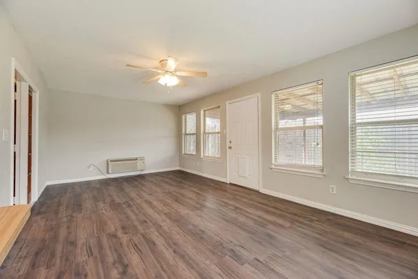 an empty room with wooden floor and windows