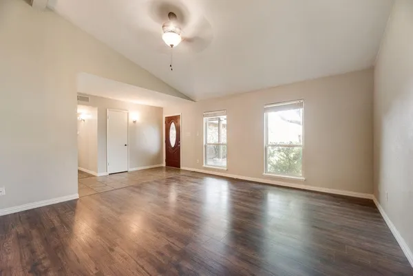 an empty room with wooden floor and windows