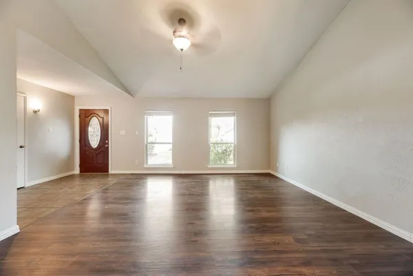 an empty room with wooden floor and window