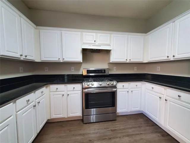 a kitchen with granite countertop white cabinets and stainless steel appliances