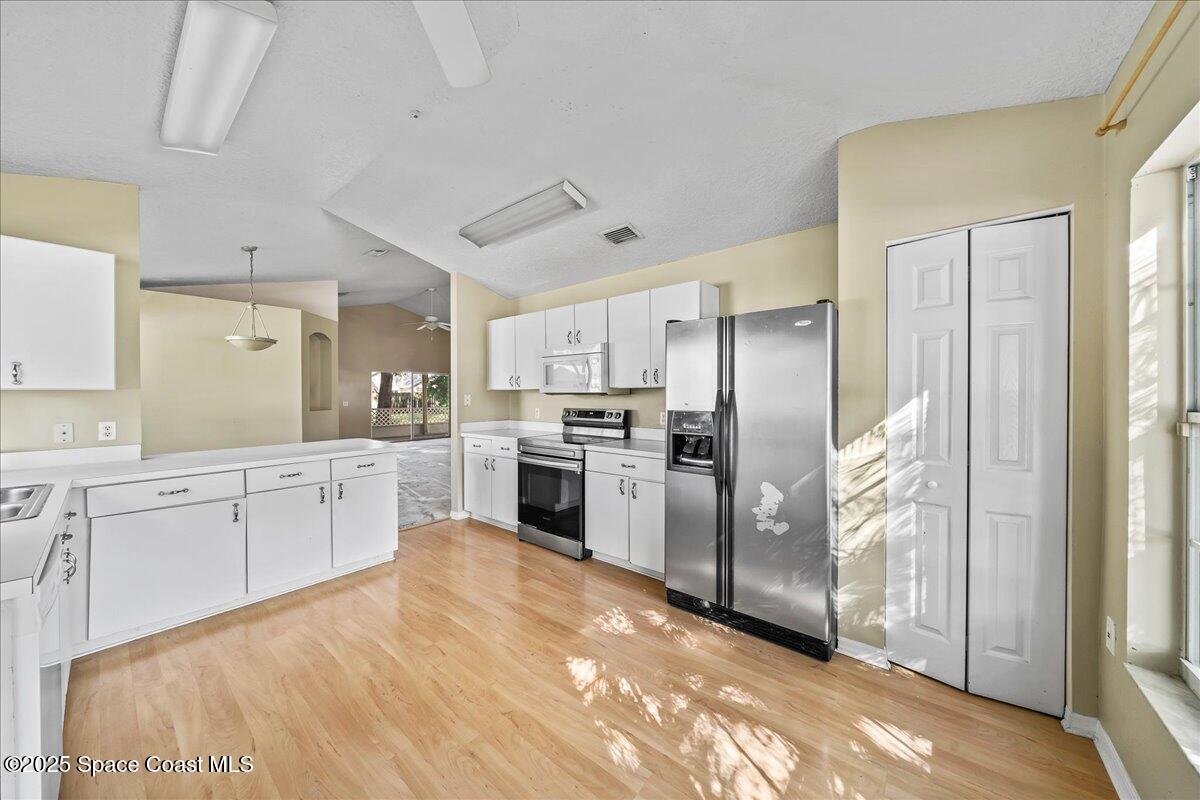 2798 Caitlin Court Melbourne, FL 32940 - Photo 6 of 27 a large white kitchen with stainless steel appliances granite countertop a refrigerator a sink a stove and white cabinets