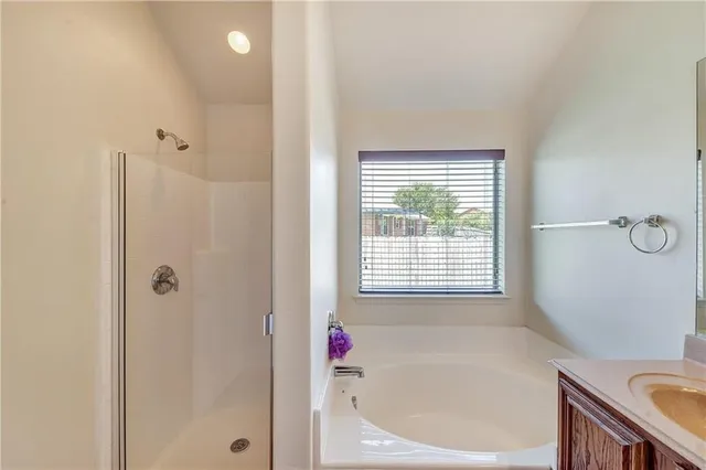 a bathroom with a bathtub a shower and a window