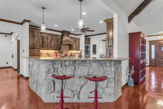 a kitchen with stainless steel appliances granite countertop a kitchen island a stove a refrigerator and a dining table with wooden floor