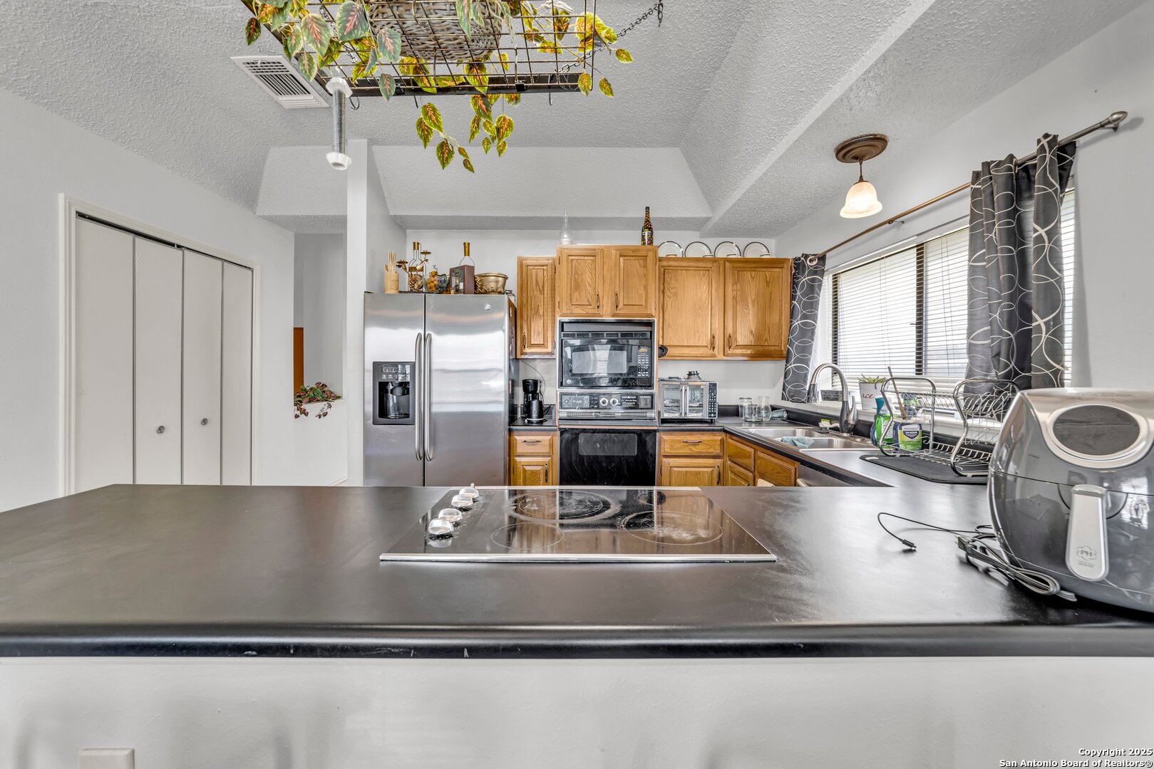 8746 Serene Ridge Drive San Antonio, TX 78239 - Photo 7 of 18 a kitchen with kitchen island granite countertop a sink a counter top space and living room view