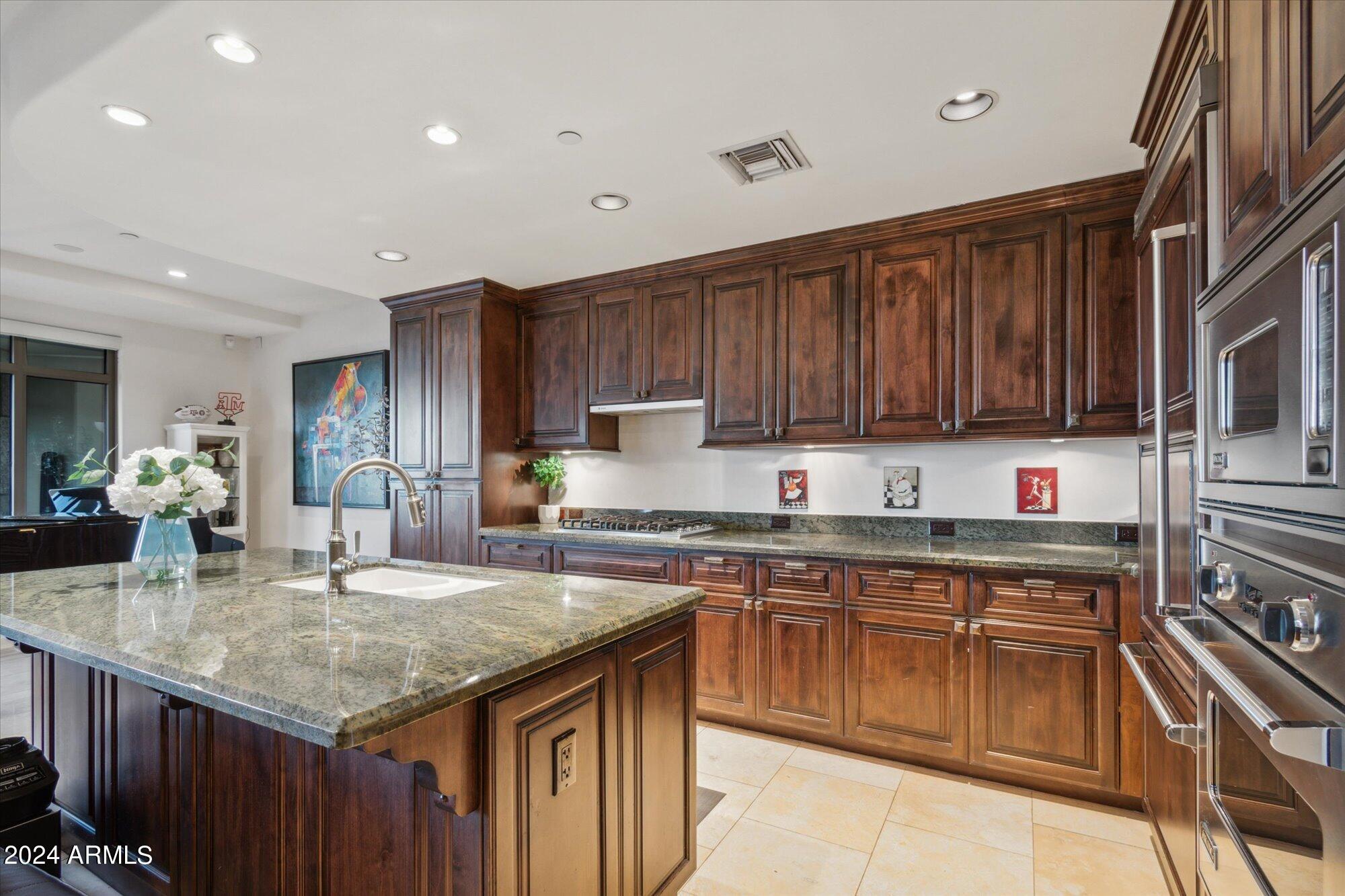 7181 East Camelback Road, Unit 206 Scottsdale, AZ 85251 - Photo 6 of 28 a kitchen with kitchen island granite countertop wooden cabinets a sink and dishwasher