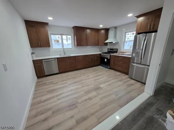 a large kitchen with stainless steel appliances a refrigerator a sink a stove a microwave and cabinets