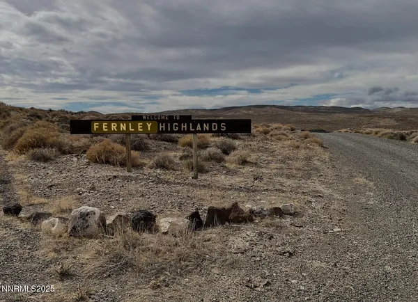 a view of a dry yard with wooden fence
