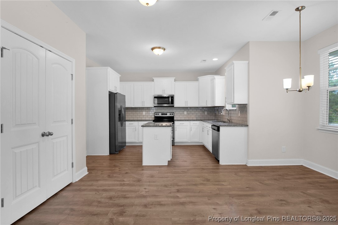 136 Loch Lane Cameron, NC 28326 - Photo 14 of 49 a kitchen with stainless steel appliances granite countertop a refrigerator a sink dishwasher a stove and white cabinets with wooden floor