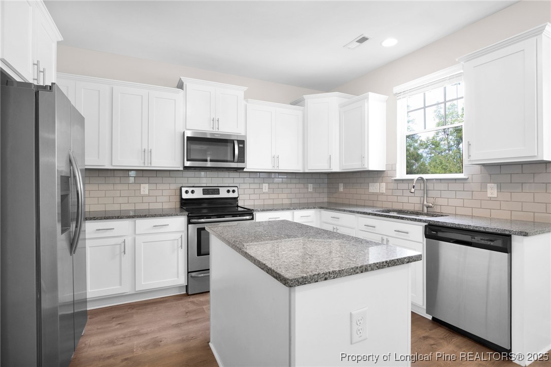 136 Loch Lane Cameron, NC 28326 - Photo 15 of 49 a kitchen with granite countertop white cabinets appliances a window and a sink