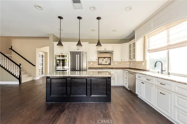 a kitchen with stainless steel appliances granite countertop wooden floors and white cabinets