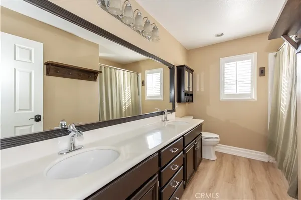 a bathroom with a double vanity sink a toilet and a mirror