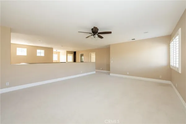 an empty room with windows and ceiling fan