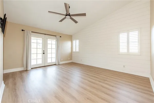an empty room with wooden floor fan and windows