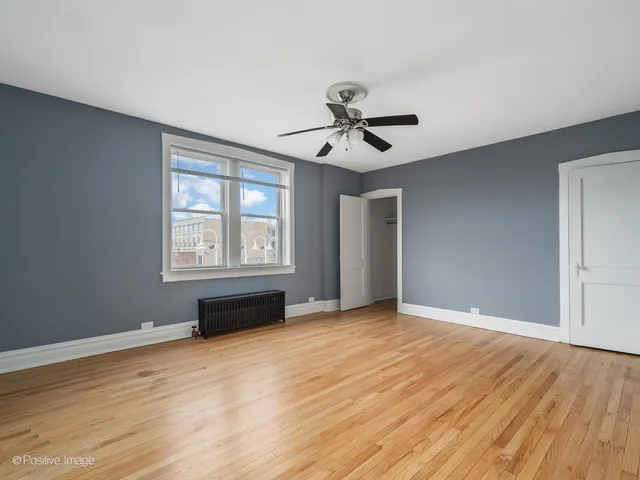 a view of empty room with wooden floor and fan