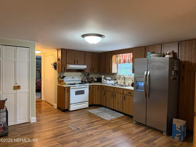 a kitchen with granite countertop a refrigerator stove top oven and sink
