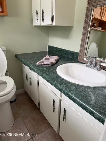 a bathroom with a granite countertop sink and a toilet