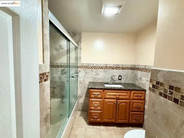 a bathroom with a granite countertop shower a sink and a stove