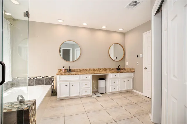 a bathroom with a granite countertop sink mirror and bathtub