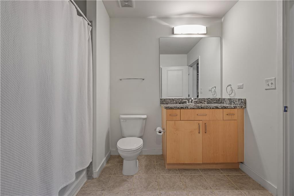250 Pharr Road Northeast, Unit 606 Atlanta, GA 30305 - Photo 12 of 31 a bathroom with a granite countertop sink toilet and mirror