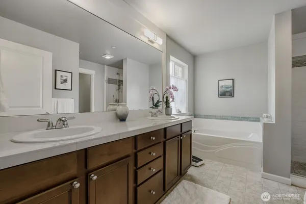 a bathroom with a sink double vanity granite tub shower and a mirror