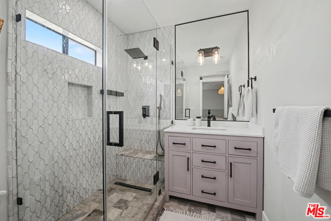 1135 West 81st Place Los Angeles, CA 90044 - Photo 22 of 28 a bathroom with a granite countertop sink a mirror a vanity and a shower