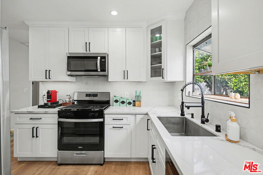 1135 West 81st Place Los Angeles, CA 90044 - Photo 10 of 28 a kitchen with white cabinets a sink and appliances