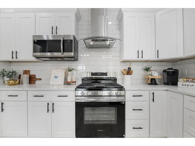 a kitchen with stainless steel appliances granite countertop white cabinets a stove top oven and a granite counter tops