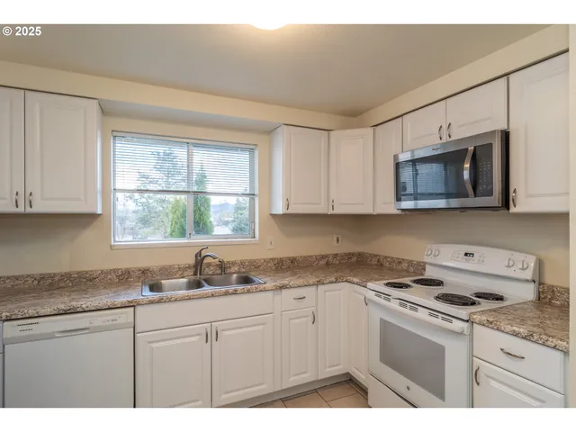 a kitchen with granite countertop white cabinets window and appliances
