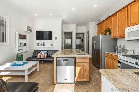 a kitchen with kitchen island granite countertop a stove a sink a refrigerator a dining table and chairs