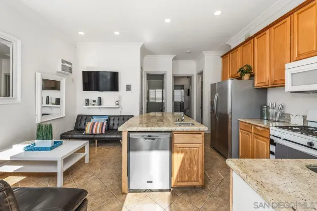 a kitchen with kitchen island granite countertop a stove a sink a refrigerator a dining table and chairs