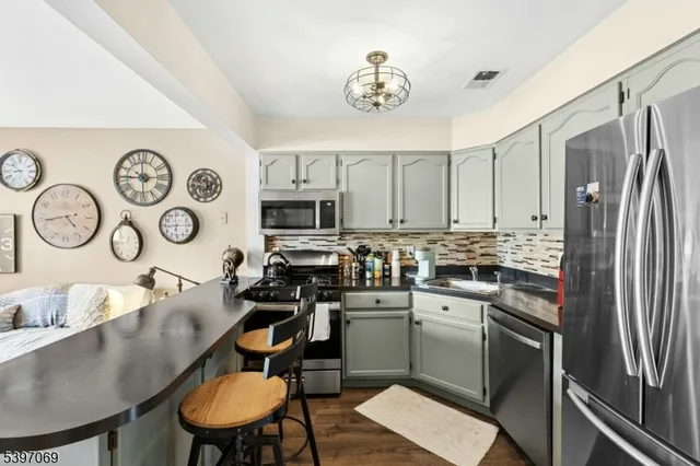 a kitchen with stainless steel appliances granite countertop a sink a stove a refrigerator and cabinets