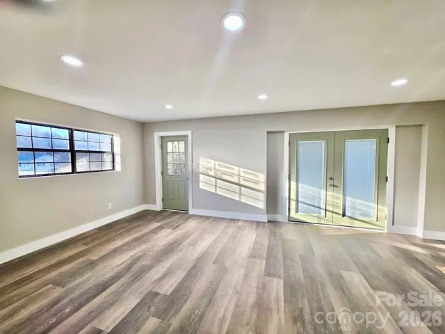 a view of an empty room with wooden floor and a window