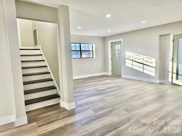 a view of a livingroom with wooden floor and stairs