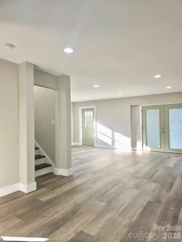 a view of an empty room with wooden floor and stairs