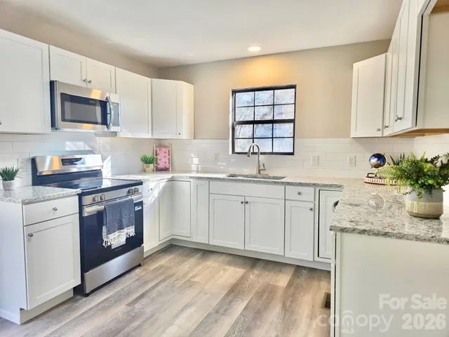 a kitchen with granite countertop white cabinets sink and stainless steel appliances