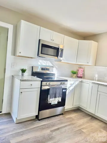 a kitchen with stainless steel appliances granite countertop a stove a microwave and white cabinets