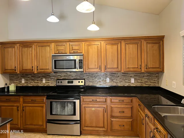 a kitchen with granite countertop a sink cabinets and stainless steel appliances