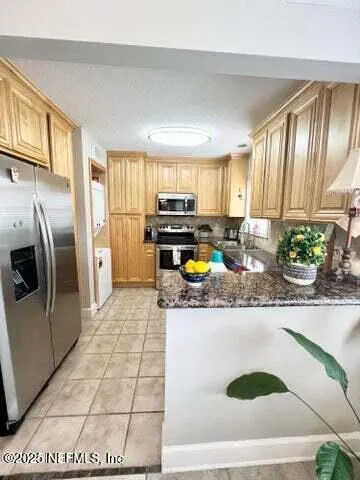 a kitchen with stainless steel appliances granite countertop a refrigerator a stove a sink a counter space and cabinets