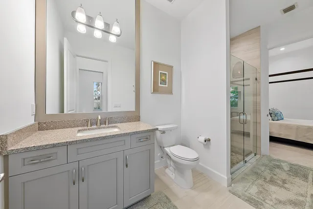 a bathroom with a granite countertop sink a toilet and a mirror