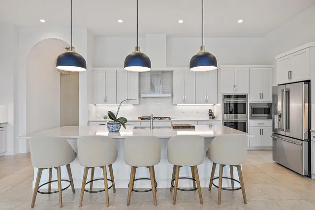 a kitchen with a stove a kitchen island a sink and a living room view