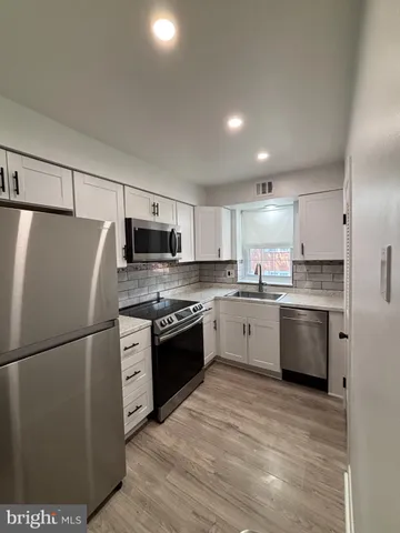 a kitchen with granite countertop a refrigerator stove top oven and sink