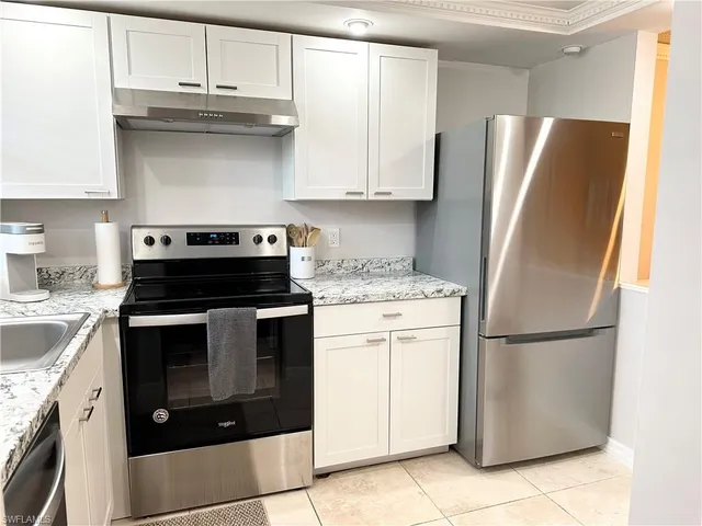 a kitchen with stainless steel appliances granite countertop a stove a refrigerator and a cabinets