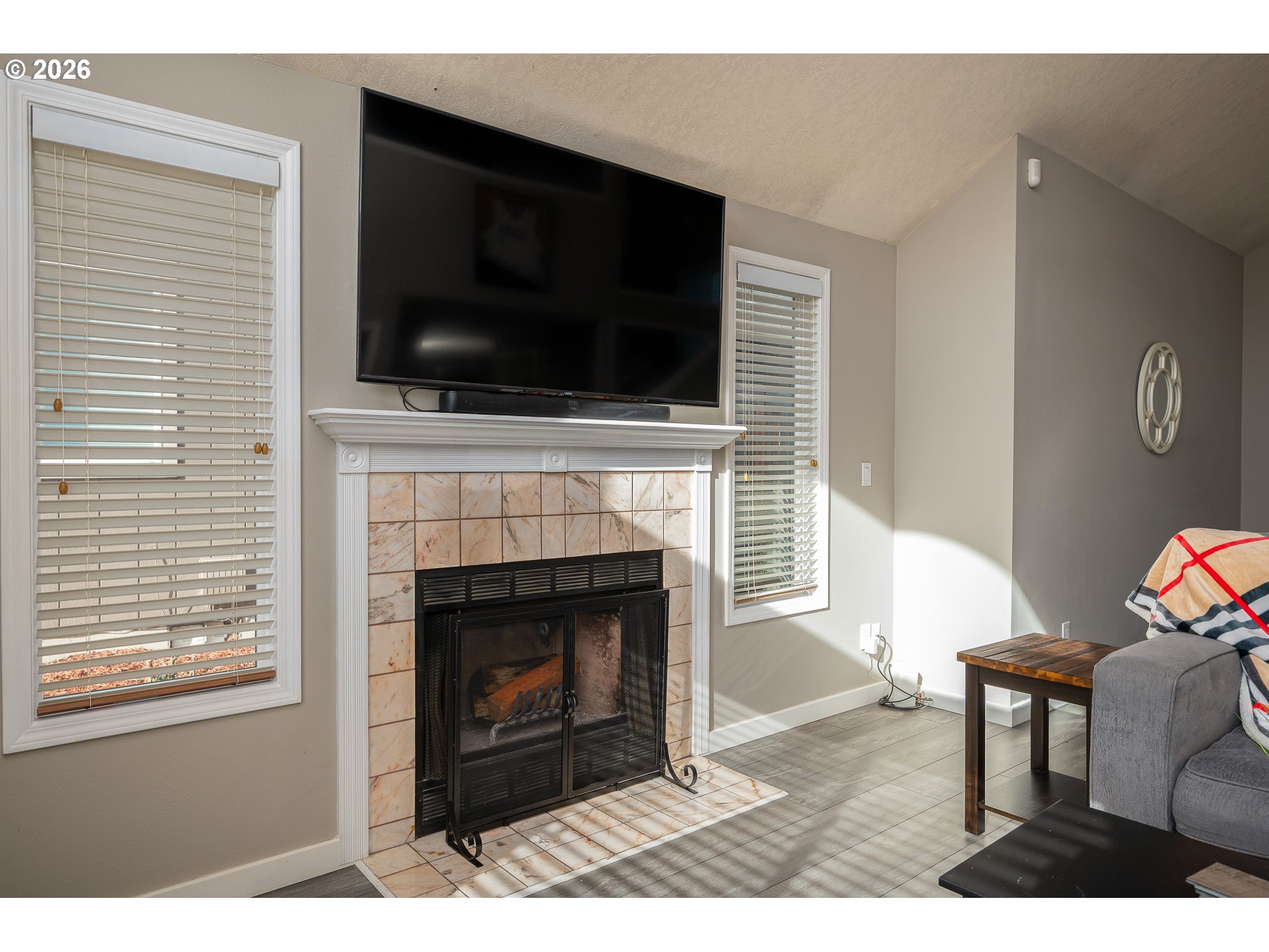8670 Southwest Stratford Court Tigard, OR 97224 - Photo 12 of 42 a living room with a fireplace a flat screen tv and a window