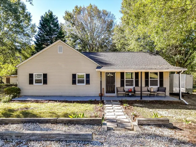 a view of a white house with a large pool plants and large tree