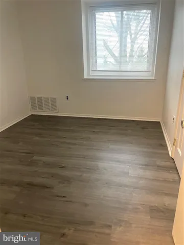 a view of an empty room with wooden floor and window