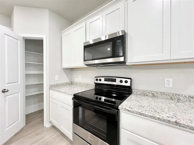 a kitchen with granite countertop cabinets stainless steel appliances and wooden floor