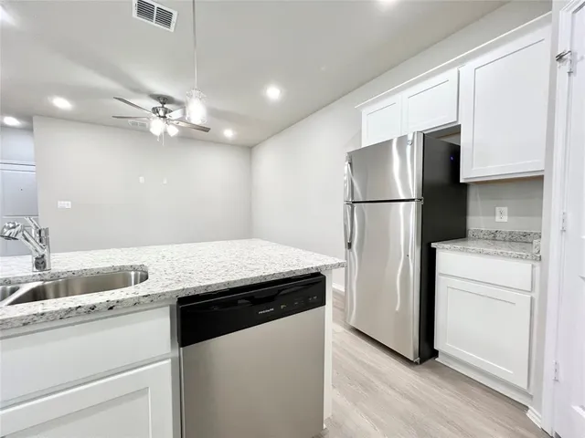 a kitchen with a refrigerator sink and cabinets