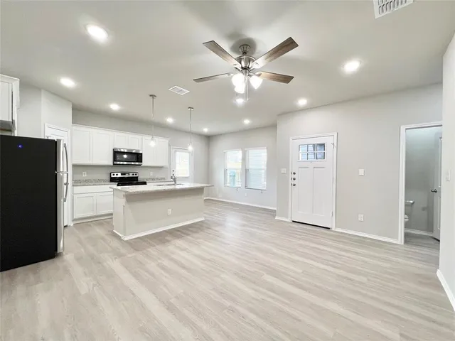 a large kitchen with kitchen island a sink stainless steel appliances and white cabinets